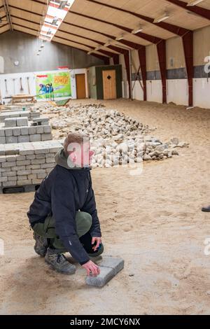 Aarhus, Denmark - November 16, 2022: Student presenting the Instruction hall of a vocational school with heaps of bricks for all kinds of practical paving instructions and training Stock Photo