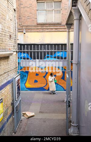 Lone Woman waiting in the urban graffiti of Brixton Station London Stock Photo