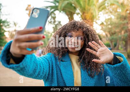 Attractive black woman smiling taking selfie with smart phone. Positive cheerful African female. Stock Photo