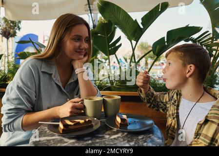 Cheese cake and coffee. Mother and son having lunch at cafe. Stock Photo