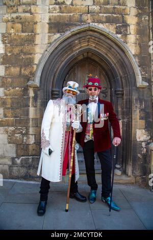 Two very smartly dressed steampunks standing in front of an old arched doorway. Stock Photo