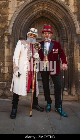 Two very smartly dressed steampunks standing in front of an old arched doorway. Stock Photo