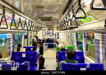 Tokyo monorail. Interior of the Hamamatsucho airport connection train to Haneda International Airport. People sitting in carriage while in station. Stock Photo