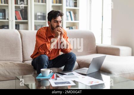 Pensive arab man working from home, looking for solution Stock Photo