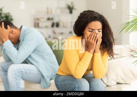Sad crying young african american woman ignores offended man after quarrel, sit on sofa, think about breakup Stock Photo