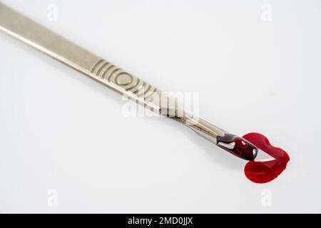 blood stained sterile stainless steel precision blade medical surgeons scalpel disposable   blade in metal handle isolated on a white background with Stock Photo