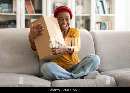Overjoyed african american woman customer receive good parcel, home interior Stock Photo