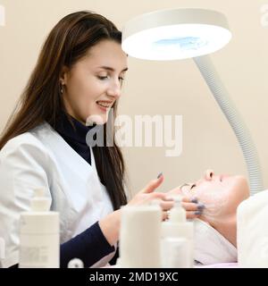 Procedure at a cosmetologist, cleansing the face of cosmetics and preparing the face for massage. Stock Photo