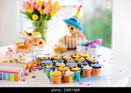 Cupcakes for kids birthday celebration. Jungle animals theme children party. Decorated room for boy or girl kid birthday. Table setting with presents Stock Photo