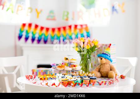 Cupcakes for kids birthday celebration. Jungle animals theme children party. Decorated room for boy or girl kid birthday. Table setting with presents Stock Photo