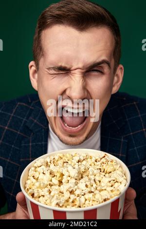Young caucasian man in 3d glasses eating popcorn Stock Photo