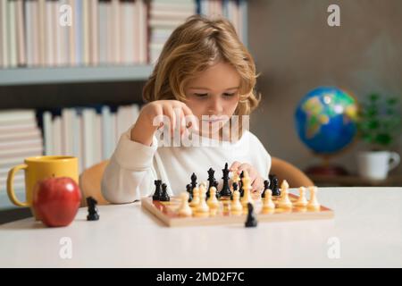 Clever concentrated and thinking child playing chess. Logic game for kids and logical thinking. Stock Photo