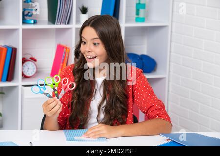 Teen school girl with scissors. Diy Ideas for children. Love and child art hobby concept. Excited face, cheerful emotions. Stock Photo