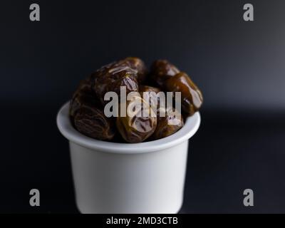 isolated dates on white bowl, black background Stock Photo