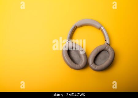 Light gray wireless over-ear headphones on an yellow background. Headphones for playing games or listening to music. Noise canceling headphones. Top v Stock Photo