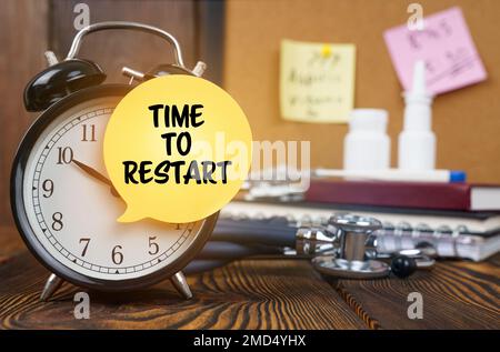 Medical concept. On the alarm clock a sticker with the inscription - TIME TO RESTART. In the background, out of focus, there is a stethoscope, a nasal Stock Photo