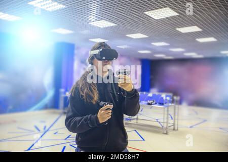 Man playing with VR set holding controllers in hands in VR club. Stock Photo