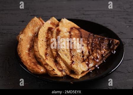 photo three pancakes in the form of a triangle lying on a plate poured with chocolate syrup Stock Photo