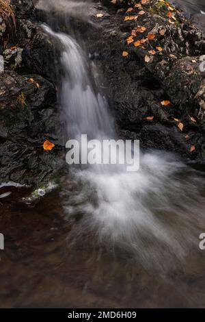 Small waterfall with colouful autumnal leaves Stock Photo