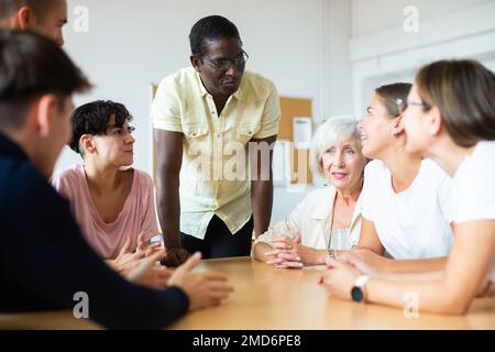 Multiracial mixed age group participating adult education class with African American tutor Stock Photo