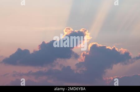 The rays of the setting sun break through the clouds. Sunset Stock Photo
