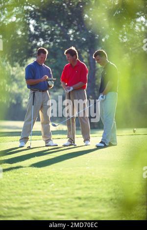 Three men standing on the next tee adding up their score Stock Photo