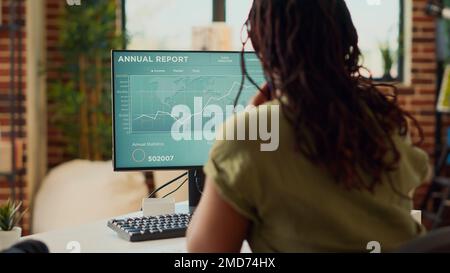 Young businesswoman working remote on data sales report, using financial diagrams on computer. Freelancer doing accounting work on online company network, analyzing internet statistics. Stock Photo