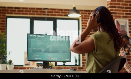 Accounting manager analyzing financial data report on diagrams, using online corporate statistics to create web sales information. Young adult working from home on finance marketing. Handheld shot. Stock Photo