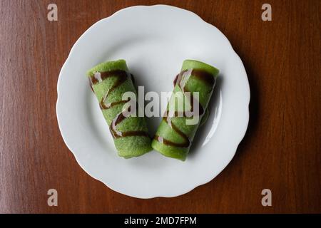 Top down view of dadar gulung (Indonesian sweet pancakes) flavoured with pandan on white plate Stock Photo