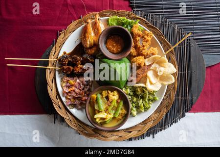 A plate of Indonesian Nasi campur (Indonesian for mixed rice) with fish and prawns, horizontal Stock Photo