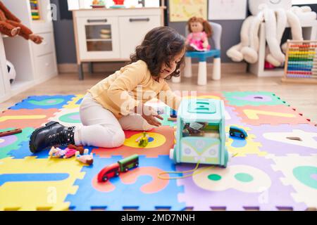 Adorable hispanic toddler playing with car toy sitting on floor at ...