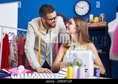 Man and woman tailors smiling confident using sewing machine at clothing factory Stock Photo