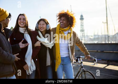 Group of multi-ethnic happy friends walking on street and talking together. Stock Photo