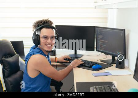 Young male programmer in casual clothes working on the computer at the table. Stock Photo