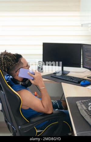 Computer programmer talks on cell phone while working from home Stock Photo