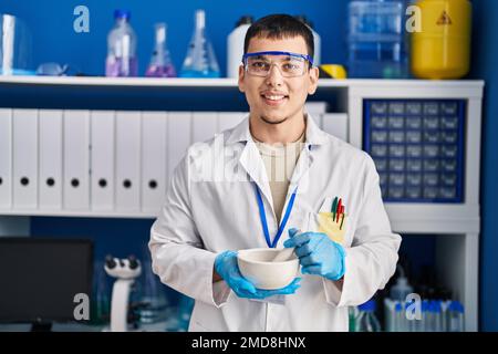 Young arab man working at scientist laboratory smiling with a happy and cool smile on face. showing teeth. Stock Photo