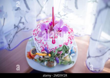 Beautiful cake at Easter decorated with fresh magnolia flowers and candle on window. consecration of cake at Easter. Homemade pasca with spring sprout Stock Photo