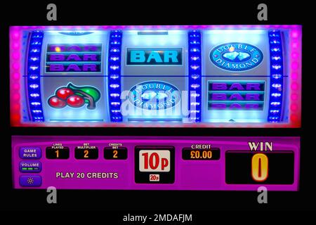 Colourful illuminated graphics on a slot machine drum wheels to attract patrons with flashing light sequences in a darkened amusement arcacde. Stock Photo