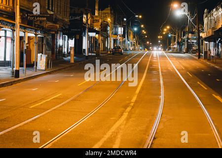 A car drives through the city of Melbourne at night on an empty  illuminated street Stock Photo