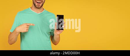 cropped man presenting phone screen. guy point finger on smartphone on yellow background. Stock Photo