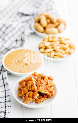 Sweet peanut brittle, peanuts and peanuts butter on the white table. Stock Photo