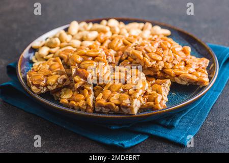Sweet peanut brittle. Tasty peanuts in caramel on the plate. Stock Photo