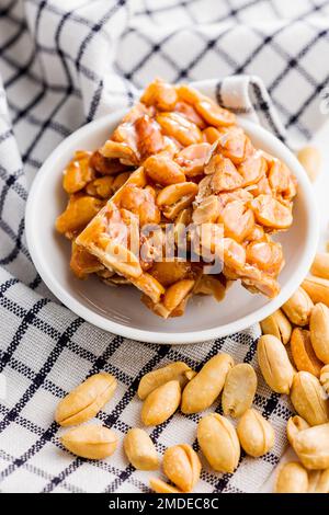 Sweet peanut brittle. Tasty peanuts in caramel on the checkered napkin. Stock Photo