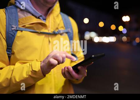 Close-up image of tourist with backpack using his smartphone on the street. Stock Photo