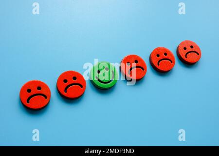 Line of sad emoticons and one happy as symbol of positivity. Stock Photo