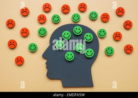 A head with happy emoticons and a sad around as a symbol of a positive attitude. Stock Photo