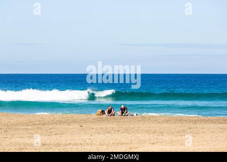 Couple meditating on Cofete beach with their backs to the sea. Fuerteventura, Canary Islands Stock Photo