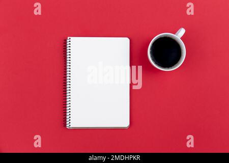 Blank notepad and coffee cup on red background, flat lay. Stock Photo