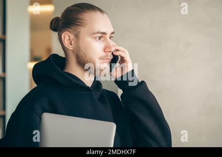 A young business man with a beard is talking on a smartphone. Stock Photo
