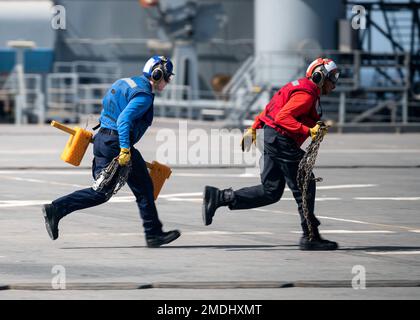 220724-F-LN908-0848  GULF OF ADEN (July 24, 2022) Airman Joshua Watson, left, from Colorado Springs, CO, and Aviation Boatswain's Mate (Handling) Airman Christopher Hopkins, from Los Angeles, sprint after removing a chock and chain from an MH-60S Seahawk, assigned to Helicopter Sea Combat Squadron (HSC) 22, aboard the Lewis B. Puller-class expeditionary sea base USS Hershel 'Woody' Williams (ESB 4), July 24, 2022. Hershel 'Woody' Williams is rotationally deployed to the U.S. Naval Forces Africa area of operations, employed by U.S. Sixth Fleet, to defend U.S., allied and partner interests. Stock Photo